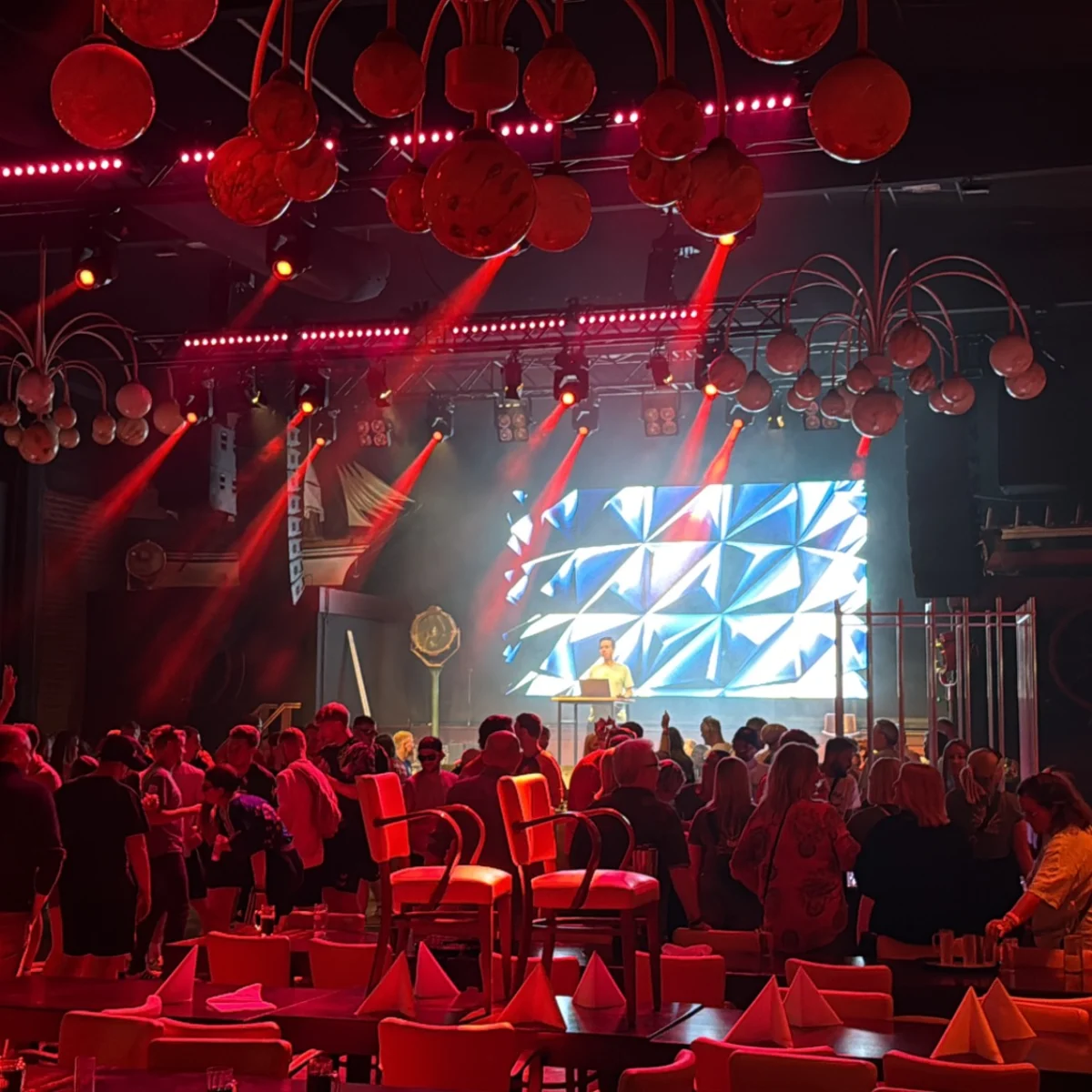 Club-Atmosphäre mit roter Beleuchtung und DJ-Performance